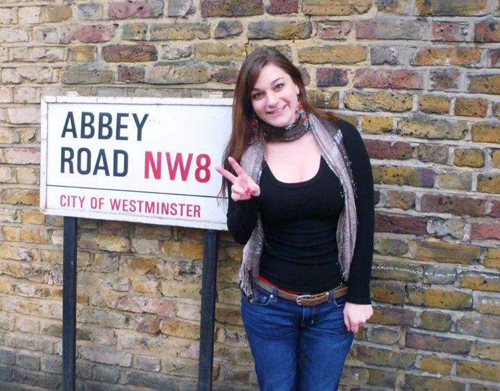 Leah Zarra posing in front of a sign for the famous Abbey Road.