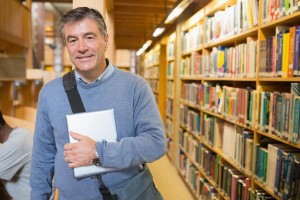 Man holding a book to his chest in a library